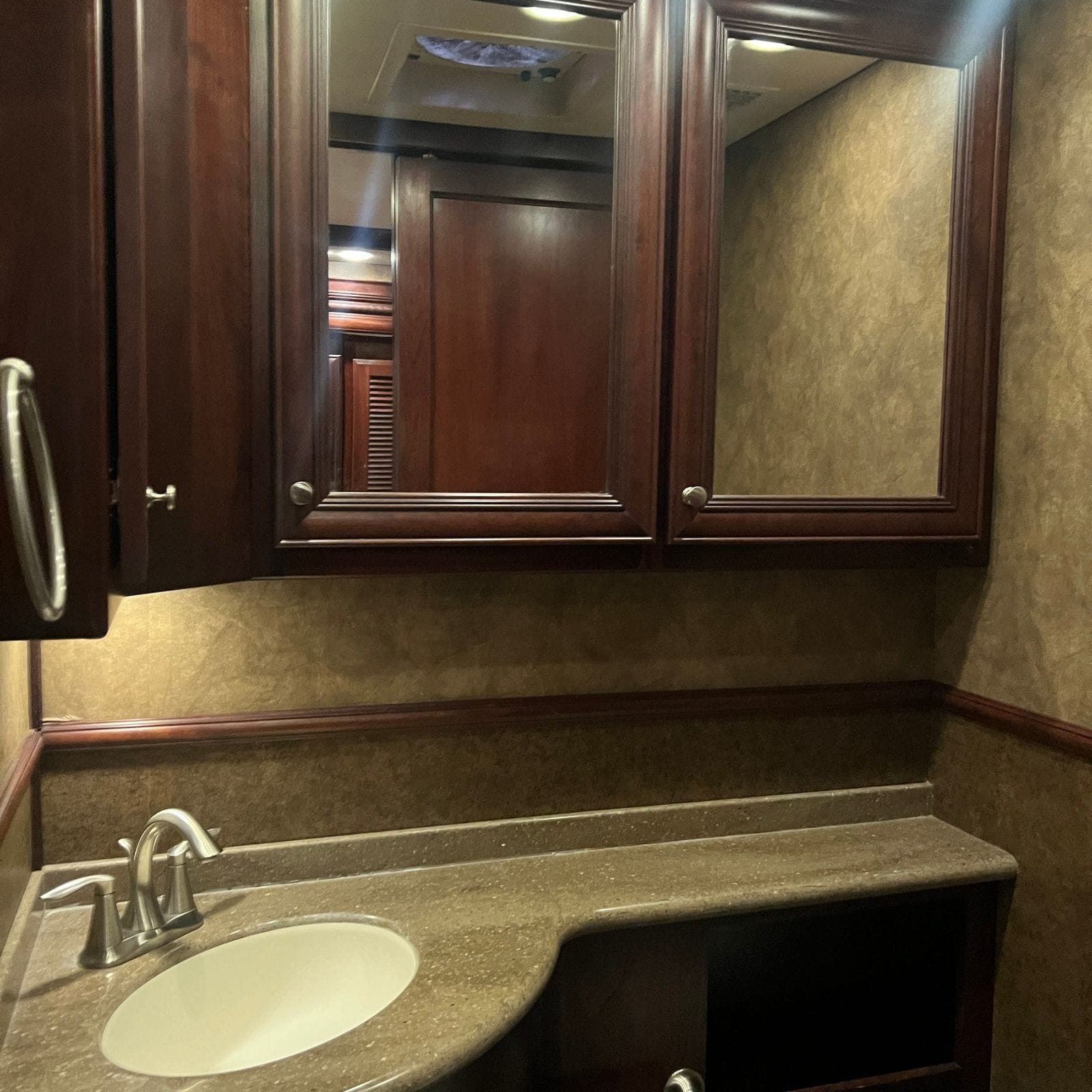2013 American Coach American Revolution 42T solid-surface vanity with oval sink and brushed-nickel faucet below twin mirrored medicine cabinets