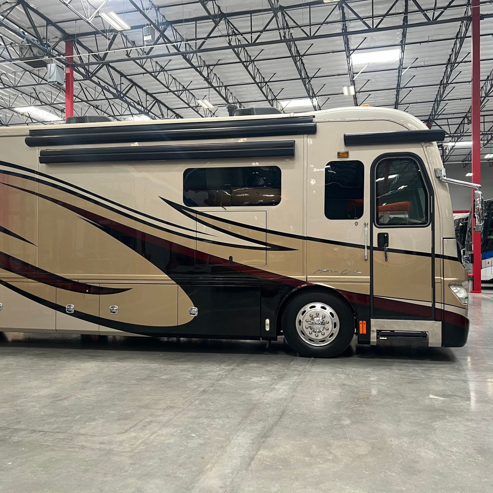 2013 American Coach American Revolution 42T passenger-side profile from further back showing full body length, two slide-outs, awning rails and basement bay doors