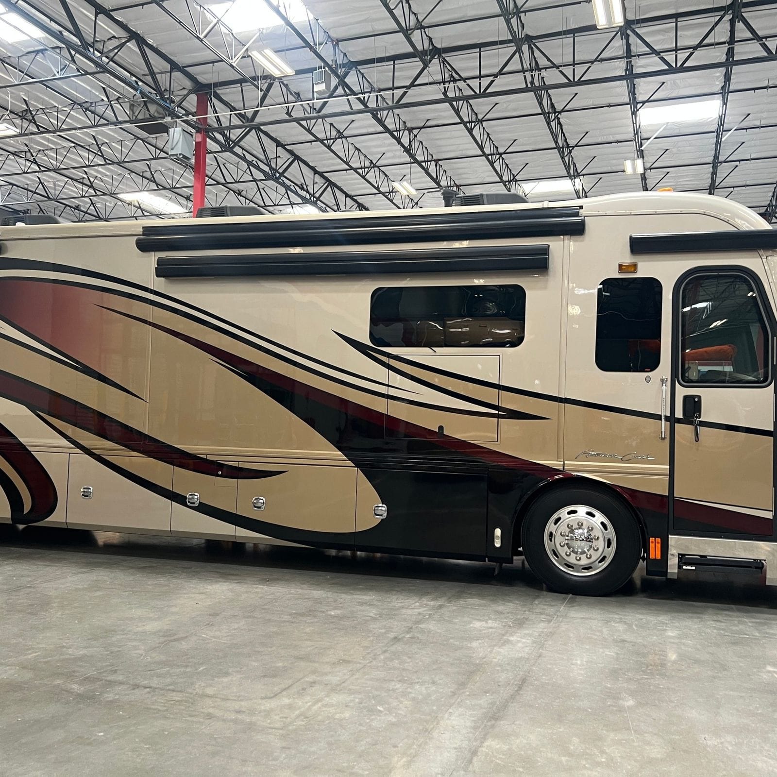 2013 American Coach American Revolution 42T close passenger-side view of the mid-body, awning rails and luggage bay doors