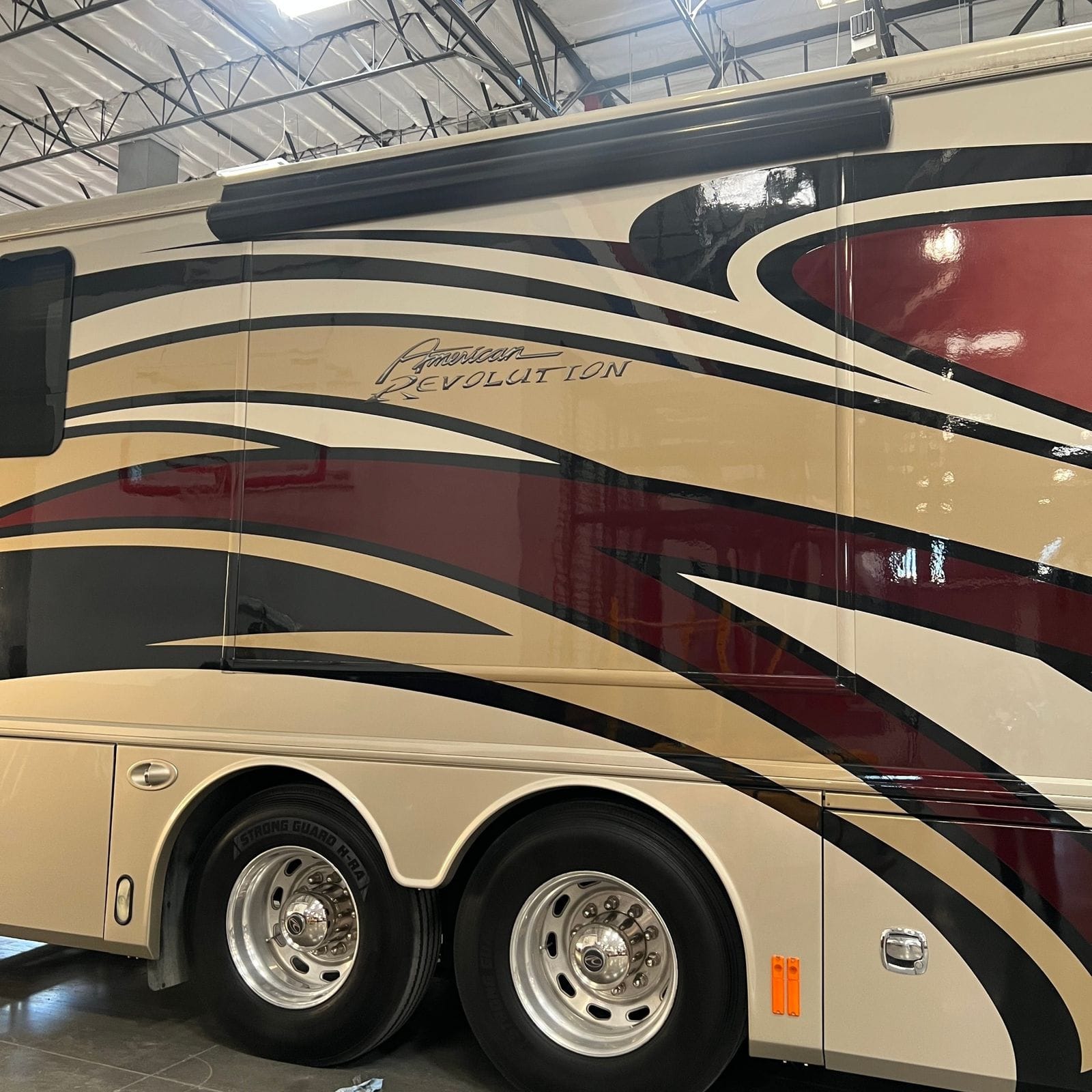 2013 American Coach American Revolution 42T American Revolution script badge above the polished aluminum drive and tag axle wheels