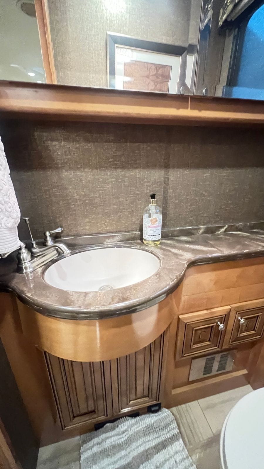 2016 Thor Tuscany 45AT half bath vanity close up with a white oval sink, brushed-nickel faucet, glass soap dispenser and maple raised-panel doors