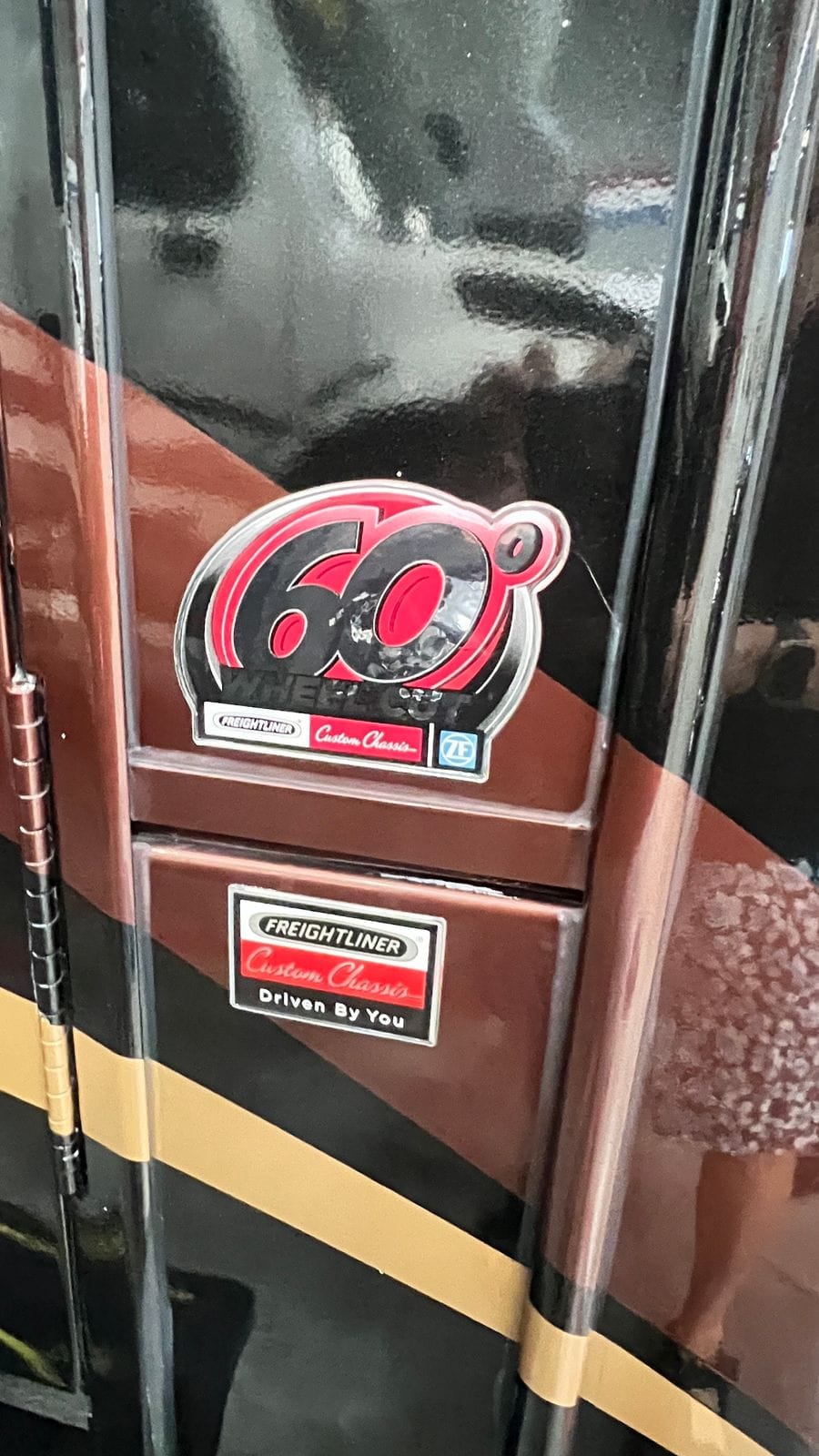 2016 Thor Tuscany 45AT sidewall badge detail on glossy black and copper paint showing a red 60-degree wheel-cut emblem and a Freightliner custom chassis plaque