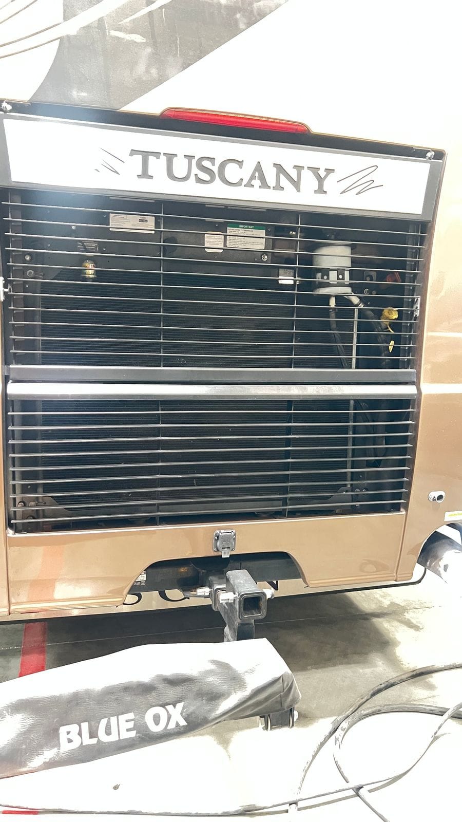 2016 Thor Tuscany 45AT rear engine view in champagne gold paint with black louvered radiator grille, Tuscany nameplate and a class IV hitch receiver