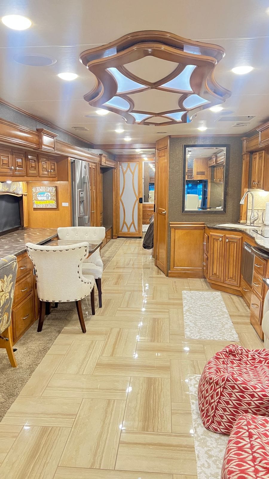 2016 Thor Tuscany 45AT wide view down the aisle from the living area, dining chairs and countertop at left, galley run and framed wall mirror at right, bedroom door at the rear