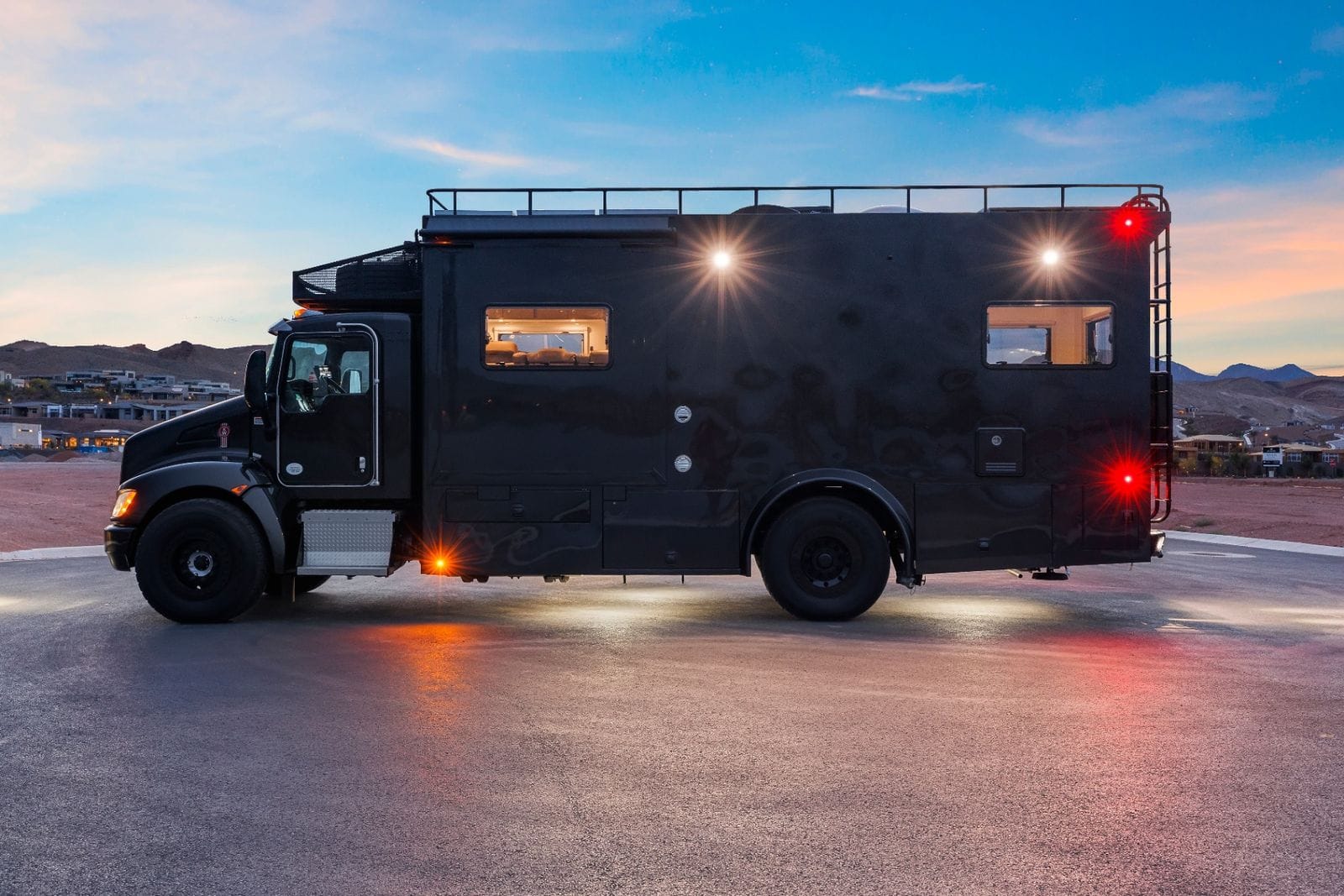 2017 Global Expedition Vehicles The Beast full driver's-side profile showing the expedition box body, over-cab roof deck and awning, rear access ladder and all-terrain tires on black steel wheels