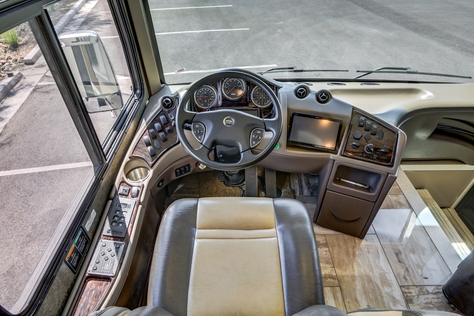 2017 Thor Venetian 40A high angle over the driver seat showing the full dash, steering wheel, Allison push-button transmission selector, switch panels and tile-look vinyl flooring