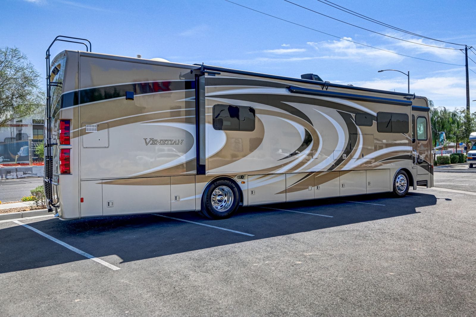 2017 Thor Venetian 40A rear passenger-side three-quarter view showing the rear cap with roof ladder, tall red tail light clusters, Venetian script on the side wall and closed storage bay doors