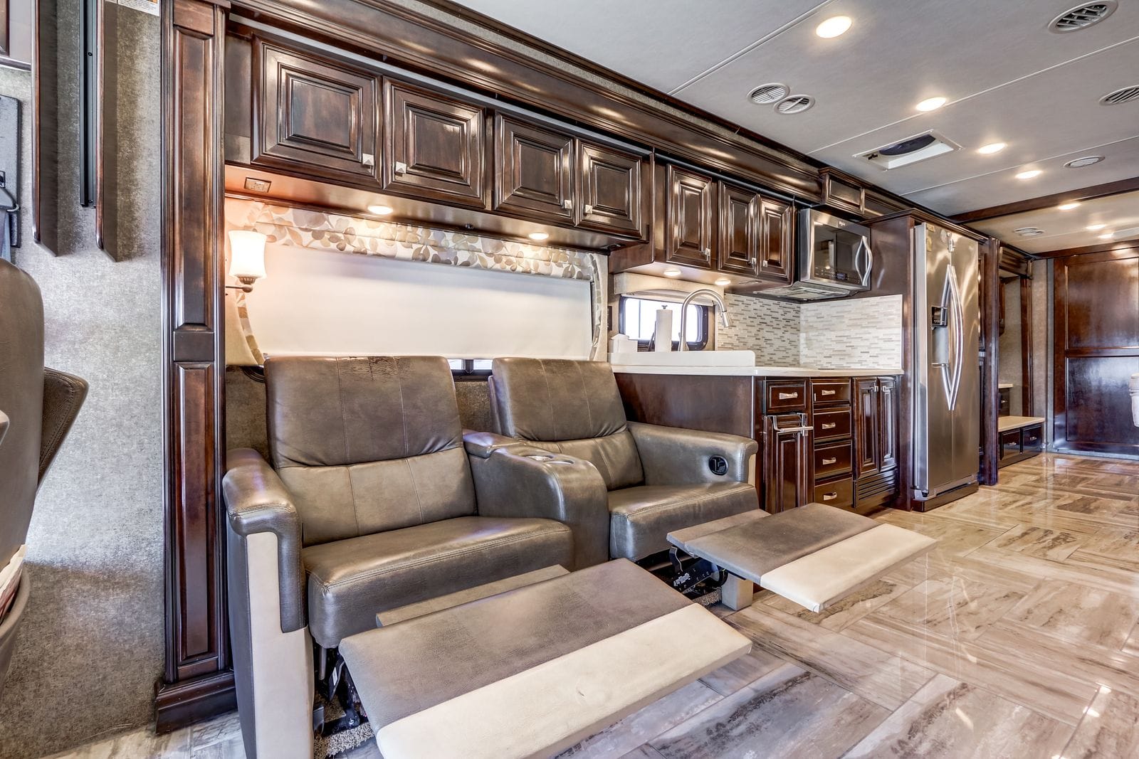 2017 Thor Venetian 40A theater seating with both recliner footrests extended, showing the power seat mechanism, leather upholstery and dark wood surround
