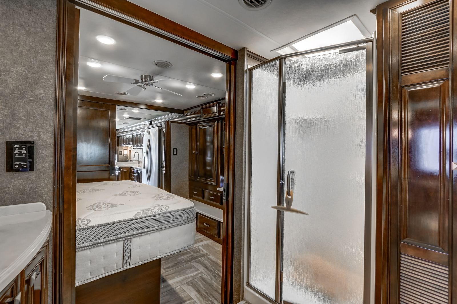 2017 Thor Venetian 40A neo-angle corner shower with pebbled obscure glass doors, chrome handle and an overhead skylight, beside the open bedroom doorway