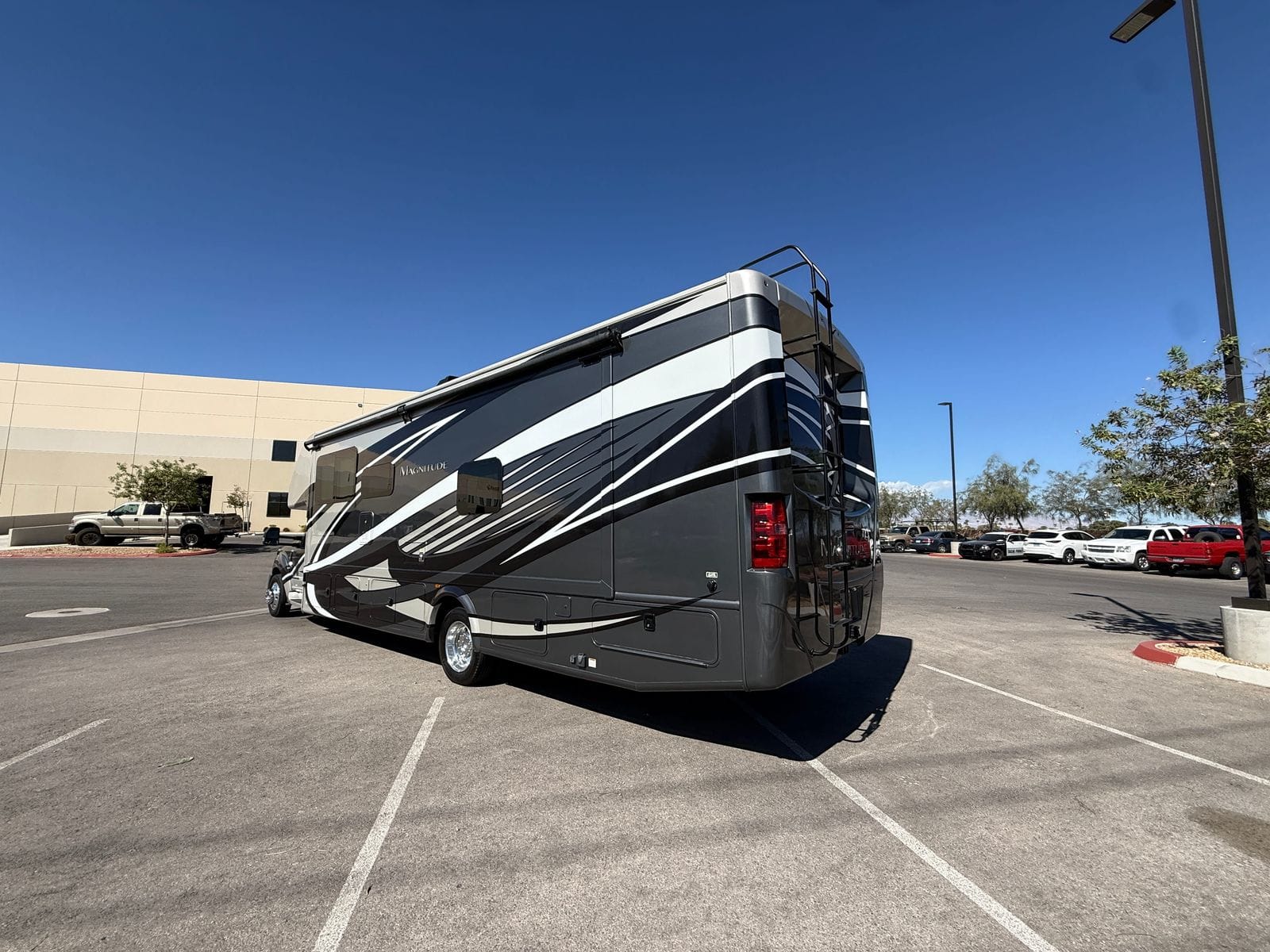 2020 Thor Magnitude BH35 rear three-quarter view from the opposite side, showing the roof-mounted air conditioners, rear ladder and tail lights