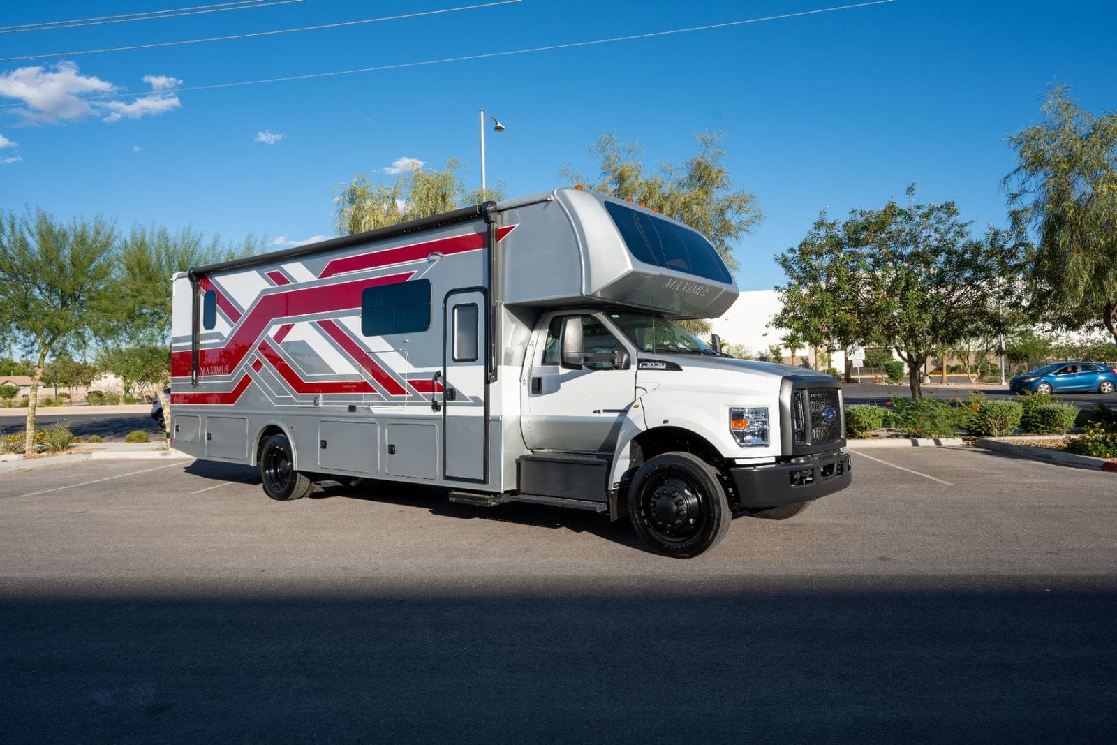 2026 Nexus Maximus 34MX front passenger-side three-quarter view of the white and red Nexus Maximus Super C with entry door and cab-over Maximus bunk