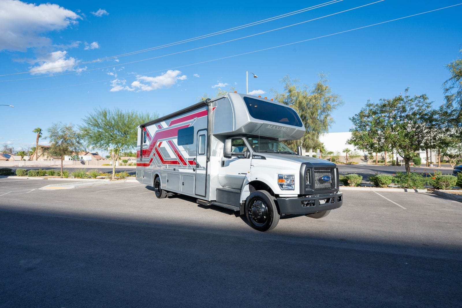 2026 Nexus Maximus 34MX front passenger-side three-quarter view showing deluxe full body paint, entry door and cab-over sleeper window