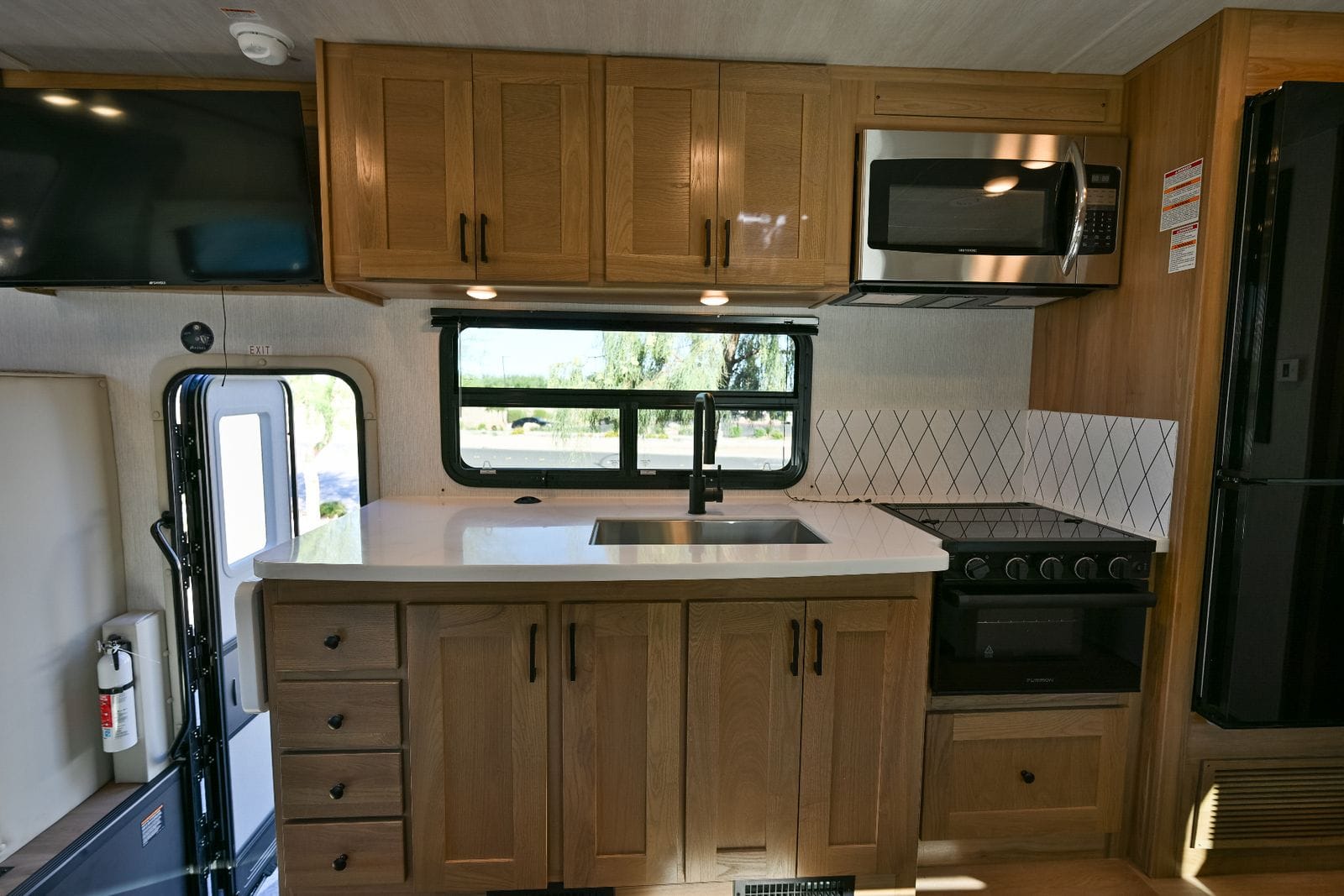 2026 Nexus Maximus 34MX galley from the entry door with quartz-look counter, sink, microwave and 12V refrigerator alongside