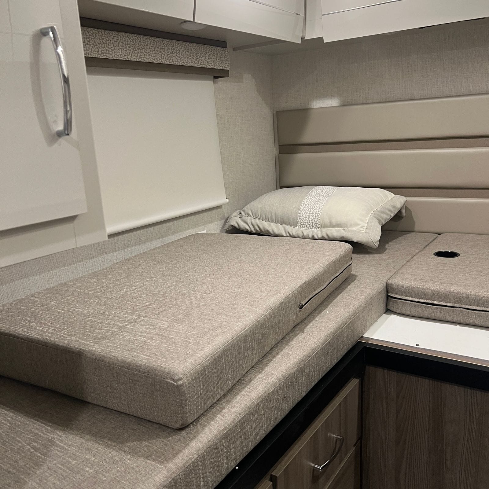 2026 Thor Delano 24XL rear twin bed with beige woven mattress, matching pillow, padded headboard panels, roller shade and overhead cabinets