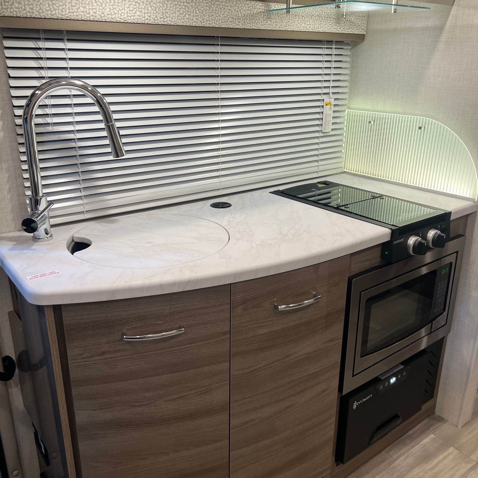 2026 Thor Delano 24XL galley counter with marble-look solid-surface top, chrome gooseneck pull-down faucet, covered round sink, two-burner glass-cover cooktop and stainless convection microwave