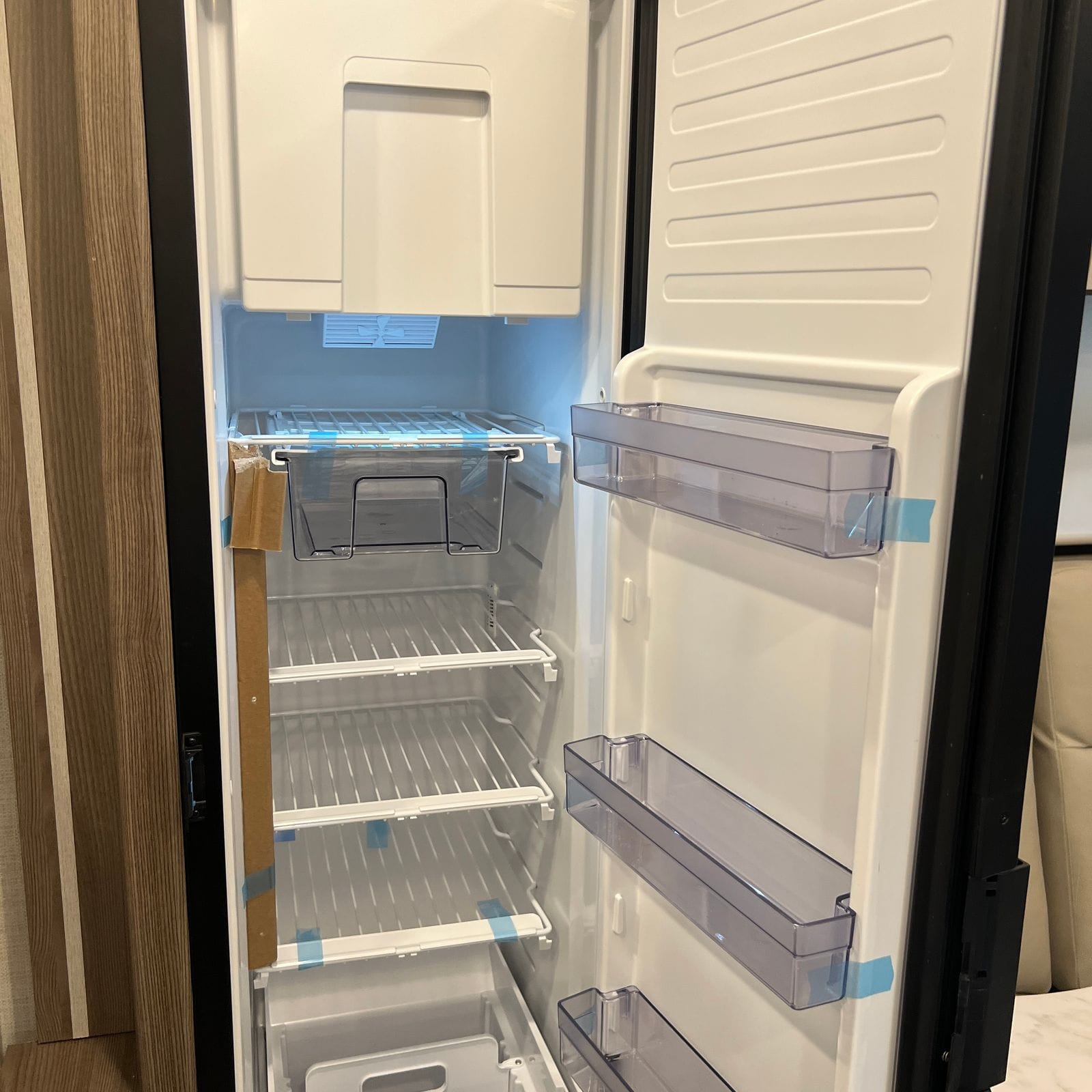 2026 Thor Delano 24XL open 12-volt refrigerator showing the freezer compartment, wire shelves and clear crisper and door bins
