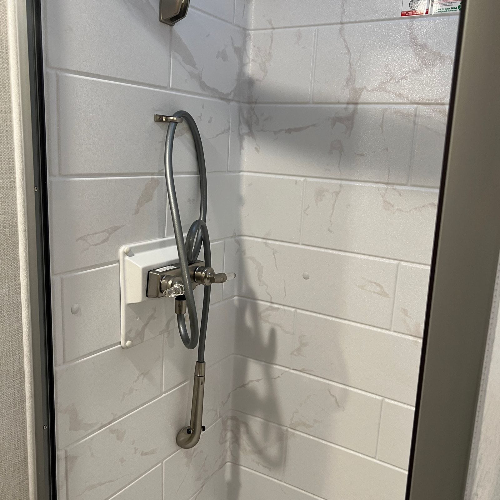 2026 Thor Delano 24XL shower enclosure with marble-look subway-tile surround, handheld sprayer on a coiled hose and a chrome valve