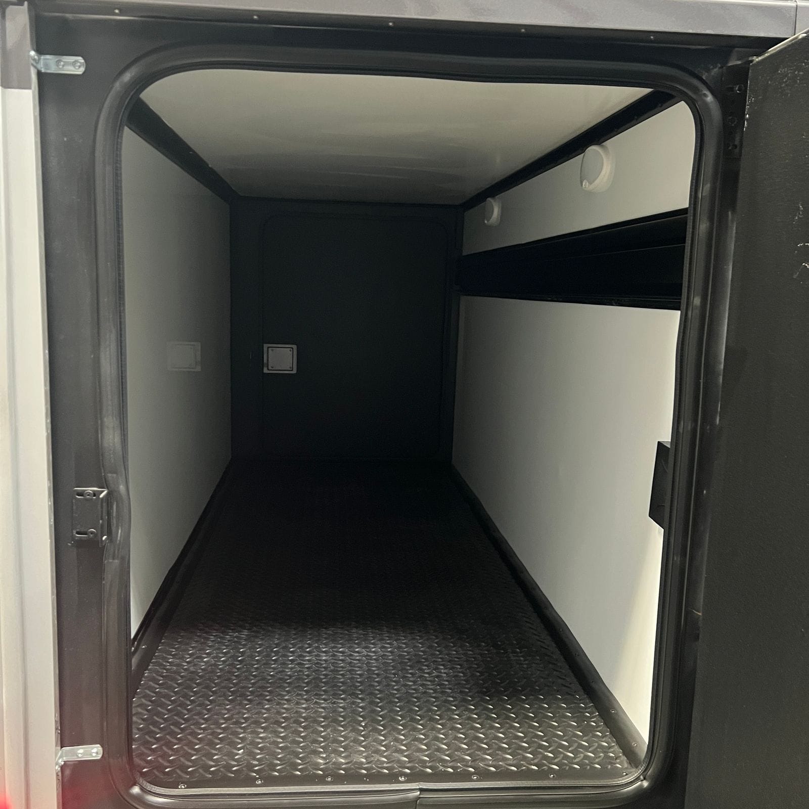 2026 Thor Delano 24XL exterior pass-through storage bay with diamond-plate floor, white lined walls and ceiling and the compartment door open