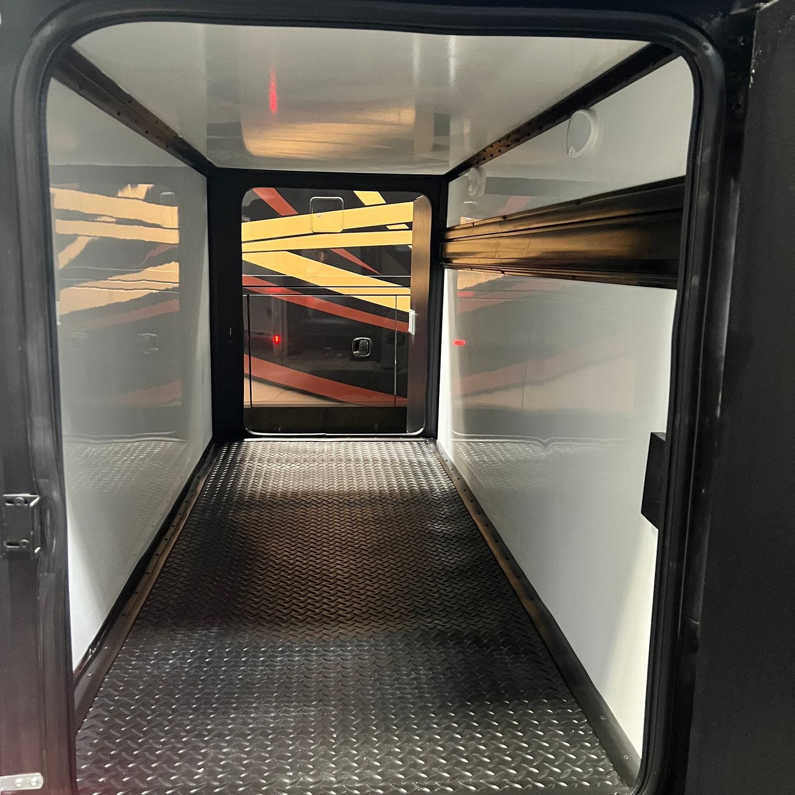 2026 Thor Delano 24XL pass-through storage bay shot with both doors open, showing the diamond-plate floor and white lined walls