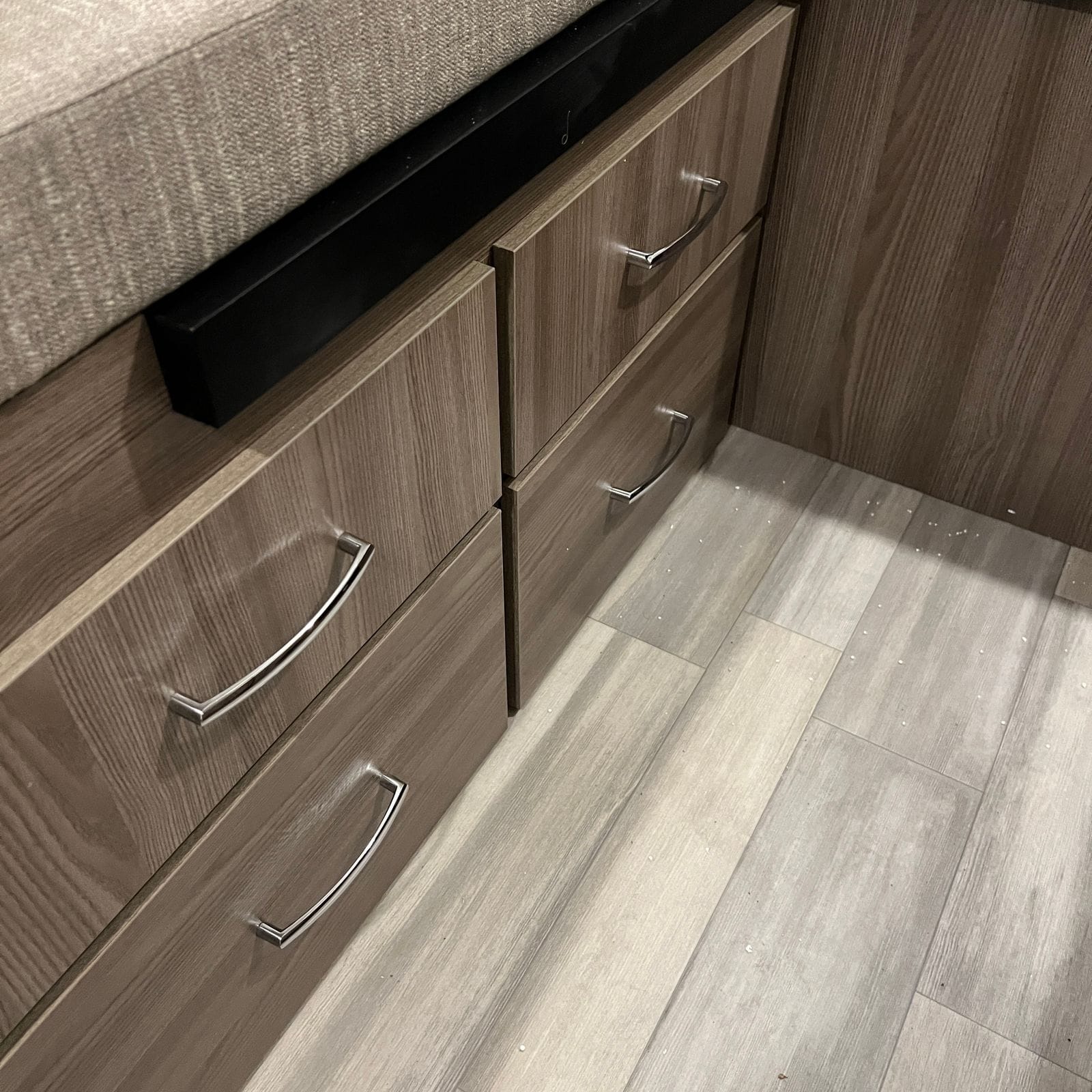 2026 Thor Delano 24XL under-bed storage drawers in wood-grain finish with chrome bow handles over wood-plank vinyl flooring