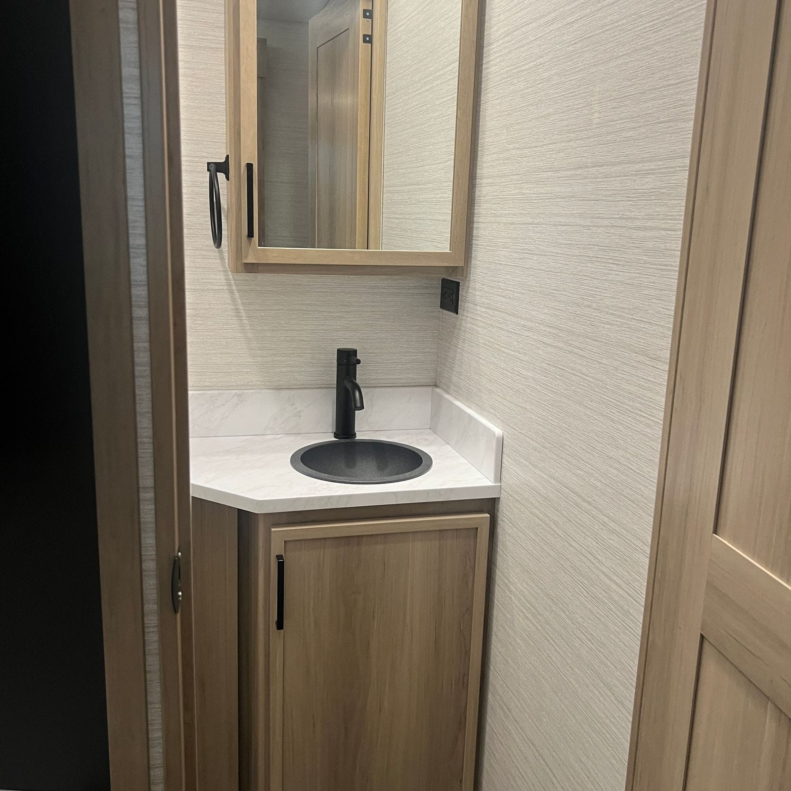 2027 Dynamax Europa S 37CA bathroom corner vanity with a round grey sink, matte black faucet, marble-look counter, mirrored medicine cabinet and towel ring