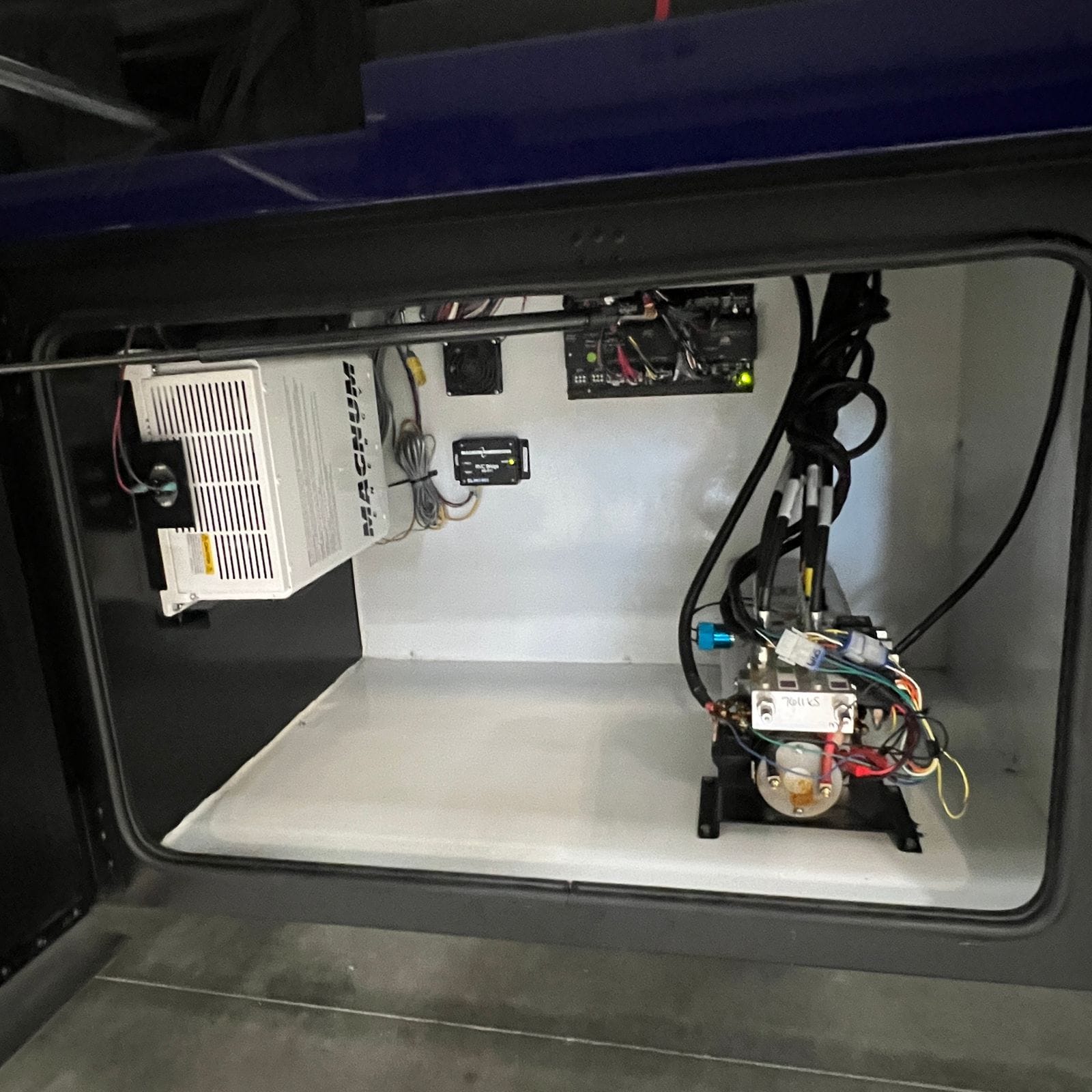 2027 Dynamax Europa S 37CA open equipment bay with a Magnum Energy inverter and charger, ventilation fan and battery disconnect solenoid