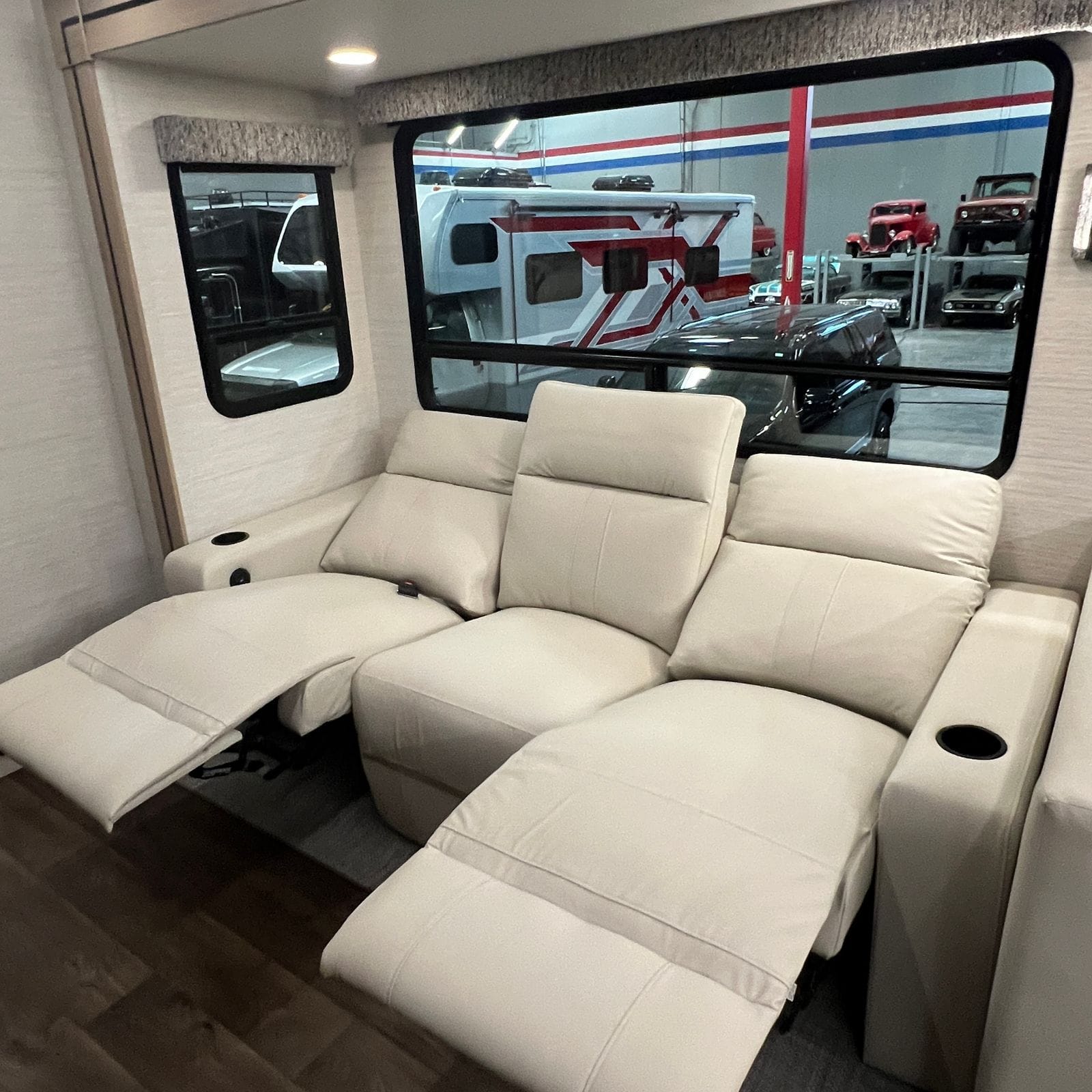 2027 Dynamax Europa S 37CA theater seating with the leather recliners extended, cup holders in the armrests and a woven area rug below