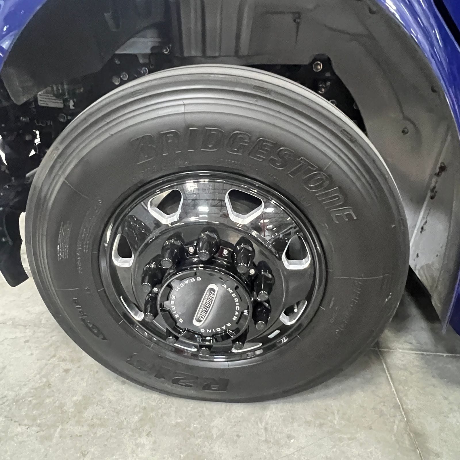 2027 Dynamax Europa S 37CA front wheel close-up with a Bridgestone tire on a polished black wheel with an American Racing coach series Freightliner center cap